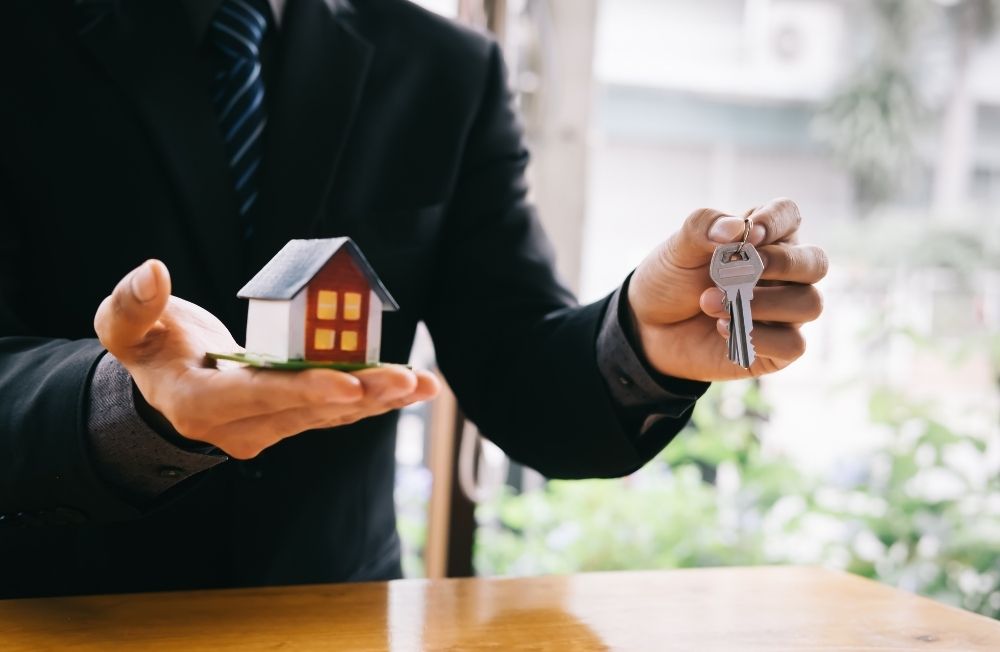 miniature house and man holding keys